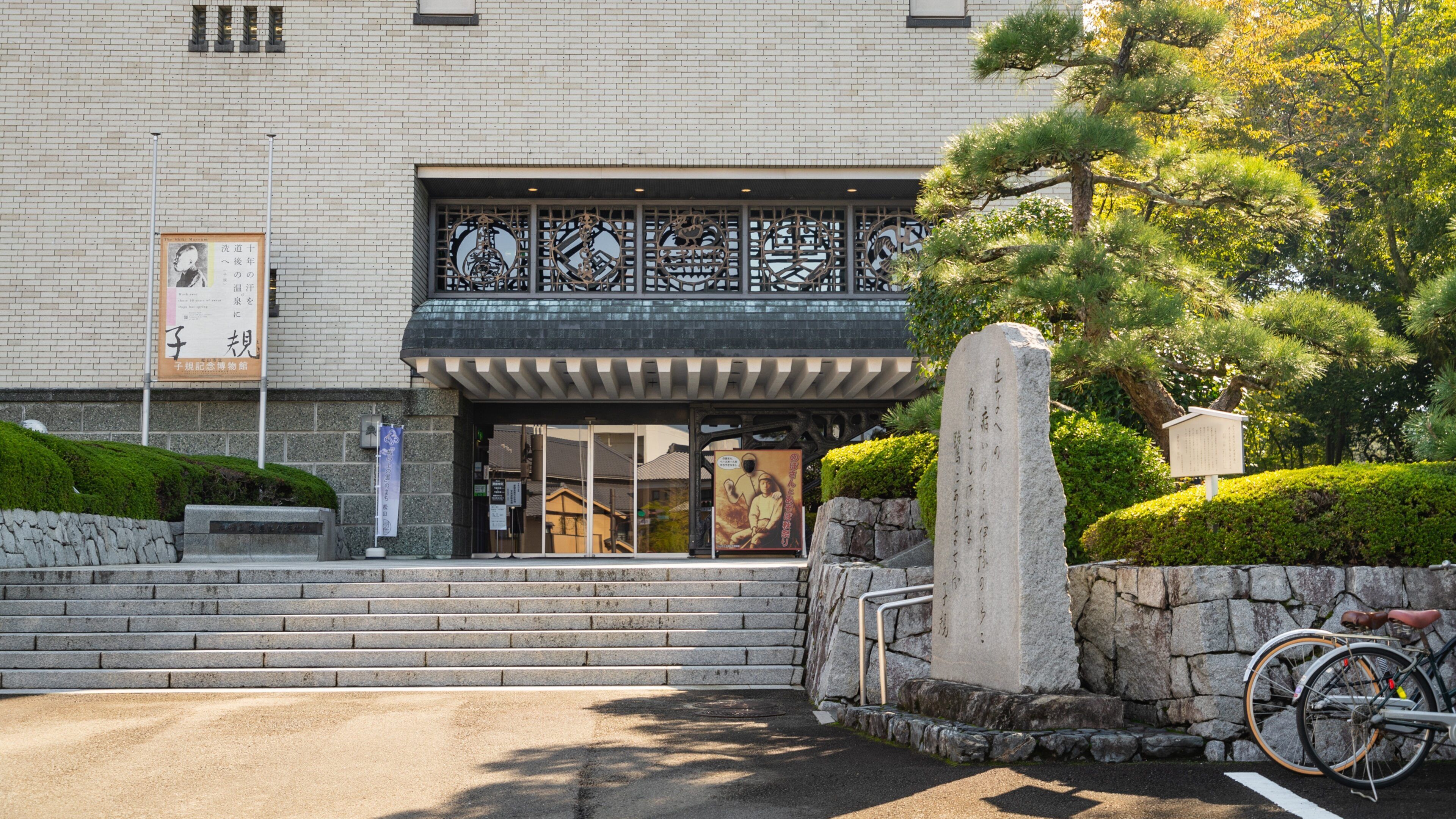 Ein traditionelles japanisches Gebäude mit einem Steinmonument und einem Fahrrad davor.