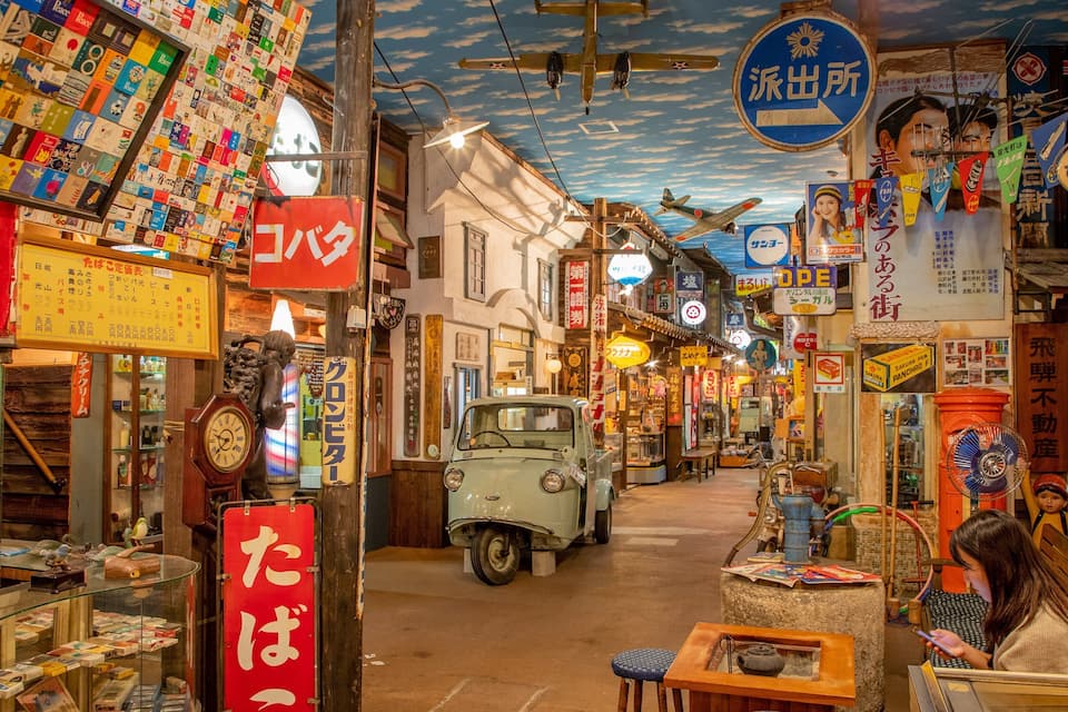 A narrow street with shops and a vintage car.