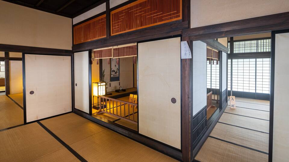 A traditional Japanese room with tatami flooring, sliding doors, and a wooden ceiling.