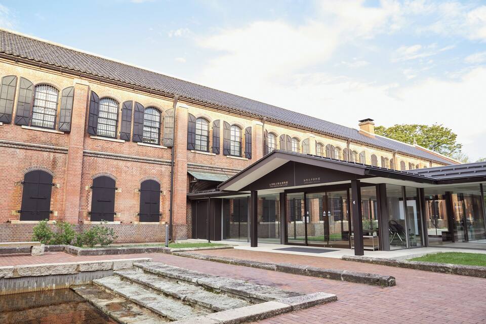 A historic brick building with large arched windows and a covered entrance.