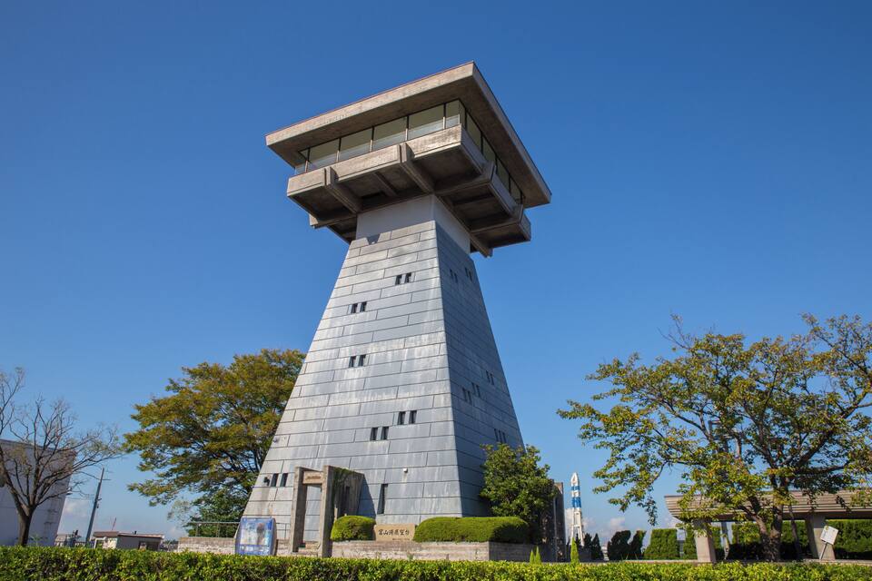 Una torre alta y moderna con un extremo plano y un letrero en su base.