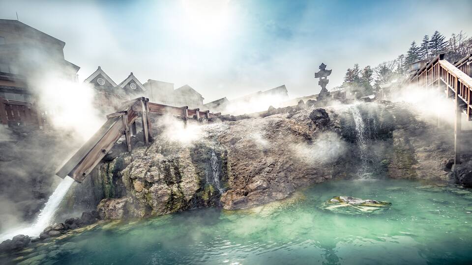 A geothermal area with a hot spring, steam, and wooden walkways.