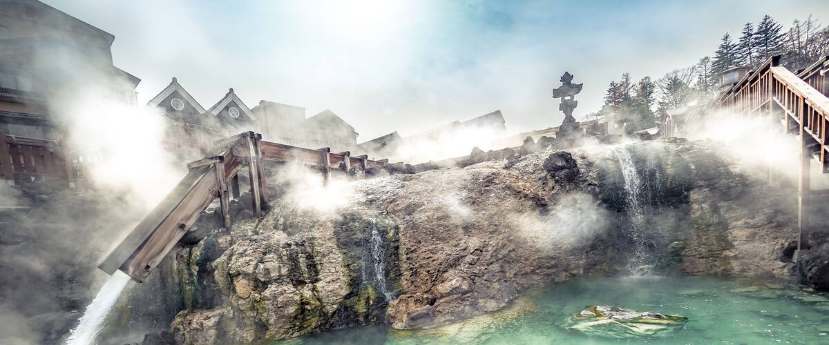 A geothermal area with a hot spring, steam, and wooden walkways.