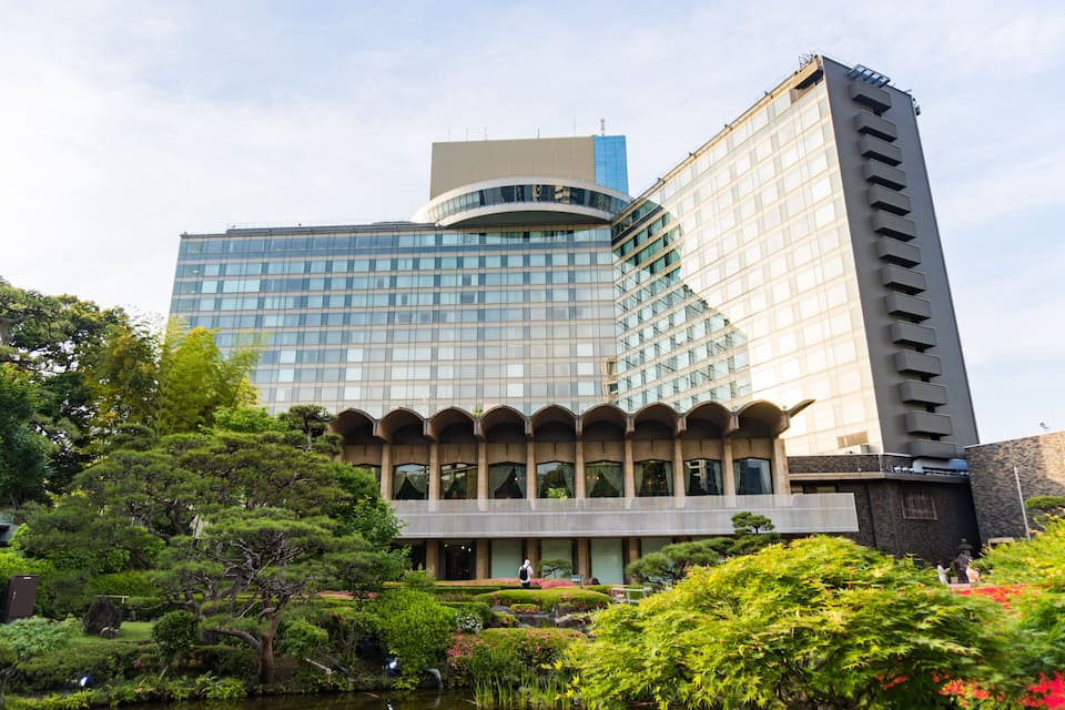A modern building with a curved glass facade, surrounded by well-maintained gardens and a pond.