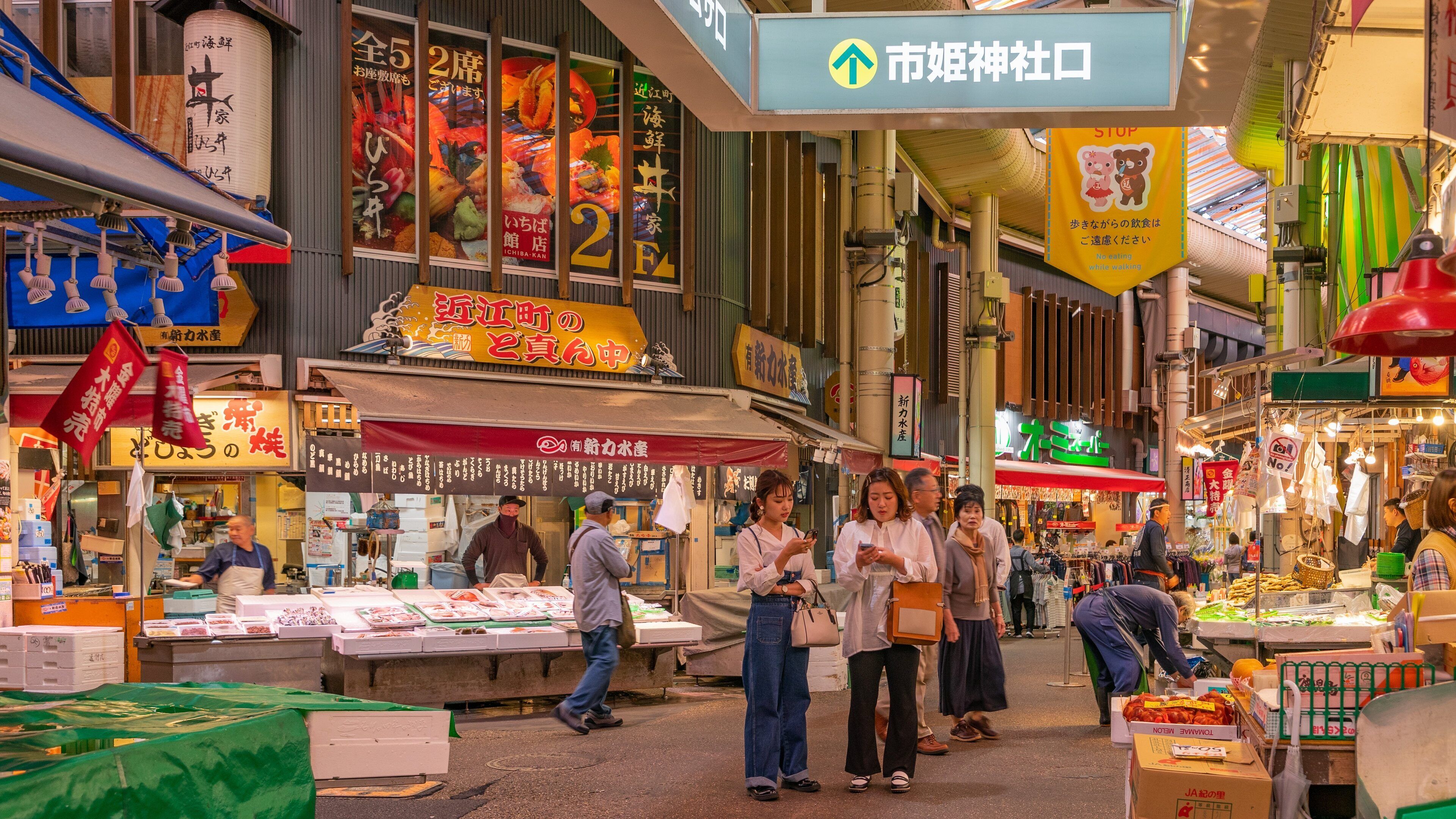 A bustling indoor market with various stalls selling seafood and other goods.