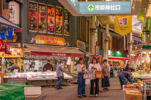 A bustling indoor market with various stalls selling seafood and other goods.