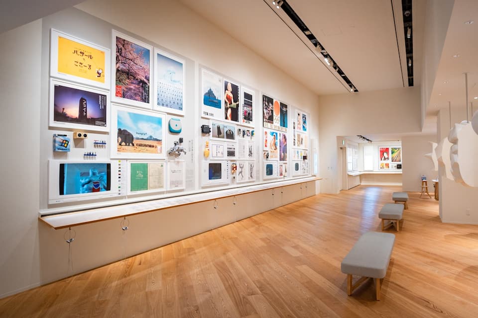 Una galería de arte con suelos de madera y una pared larga que exhibe diversos carteles y obras de arte.