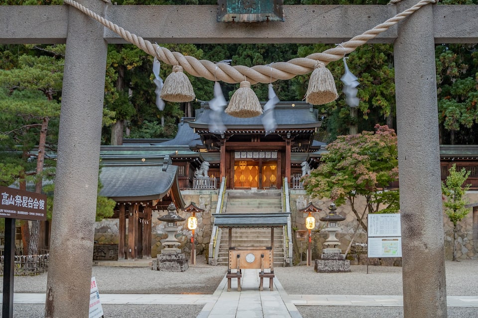 A traditional Japanese temple with a torii gate, stone lanterns, and a wooden building with a tiled entrance.