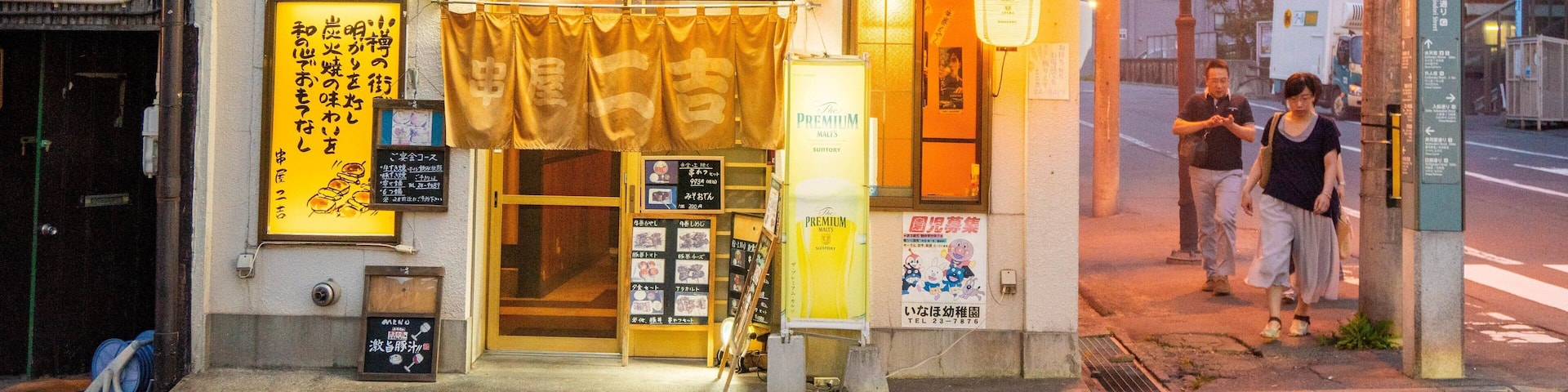 A building with Japanese signage and a storefront with illuminated signs.