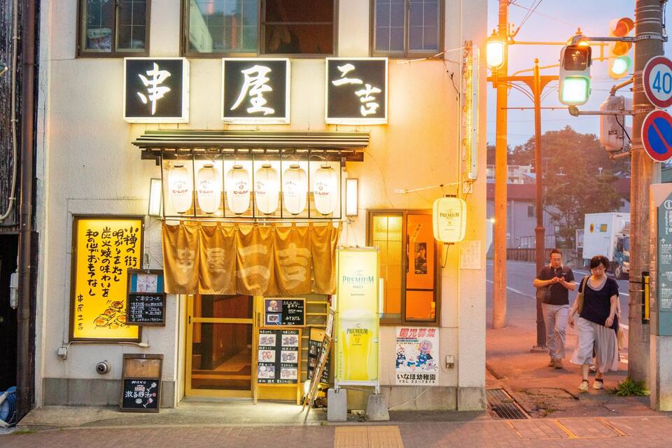 Un edificio con señalización japonesa y escaparate con letreros iluminados.