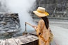 Travel woman put a basket into hot spring for cooking in Jioujhihze of Taipingshan in Taiwan