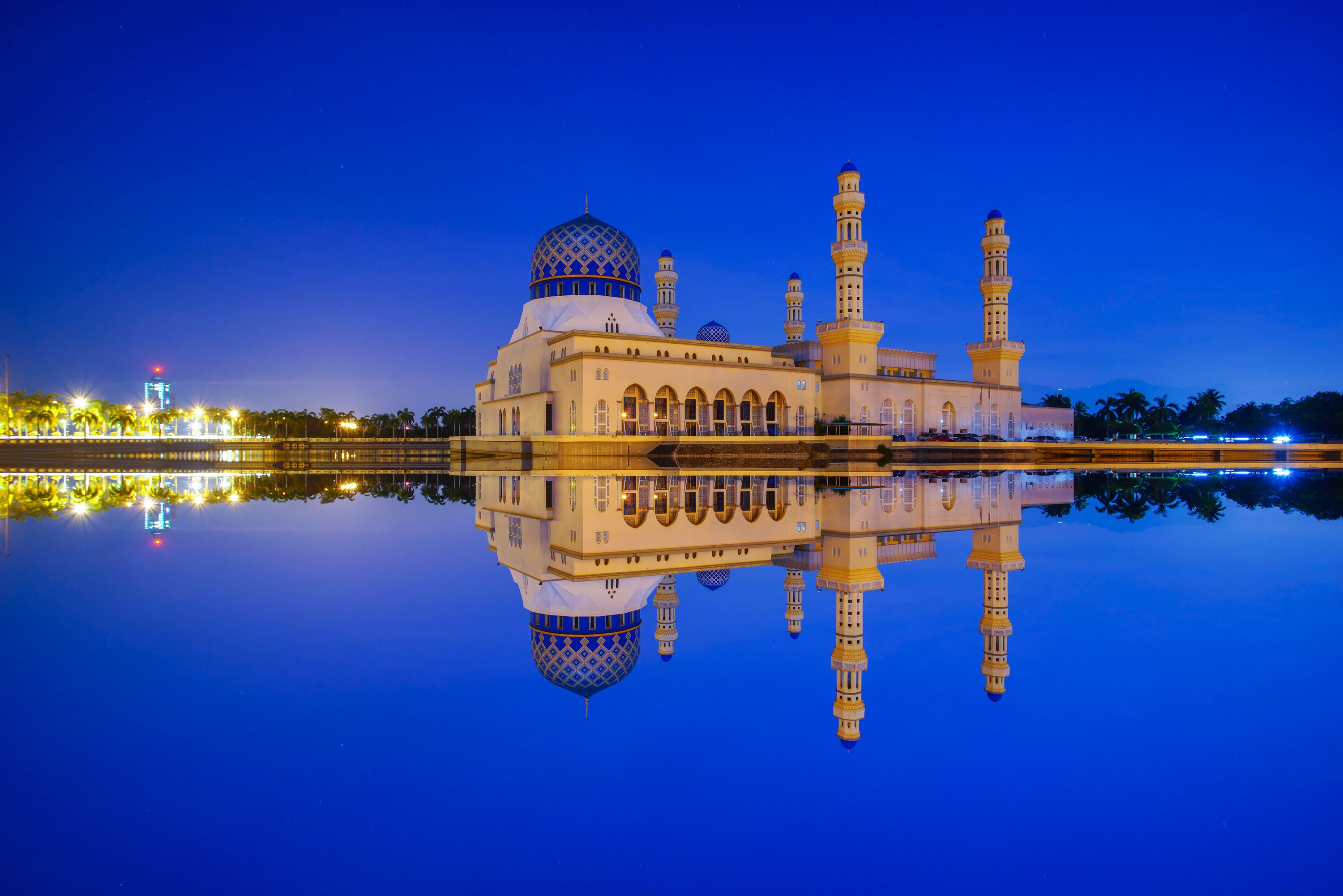 Una mezquita con una cúpula grande y dos minaretes, reflejada en aguas tranquilas.