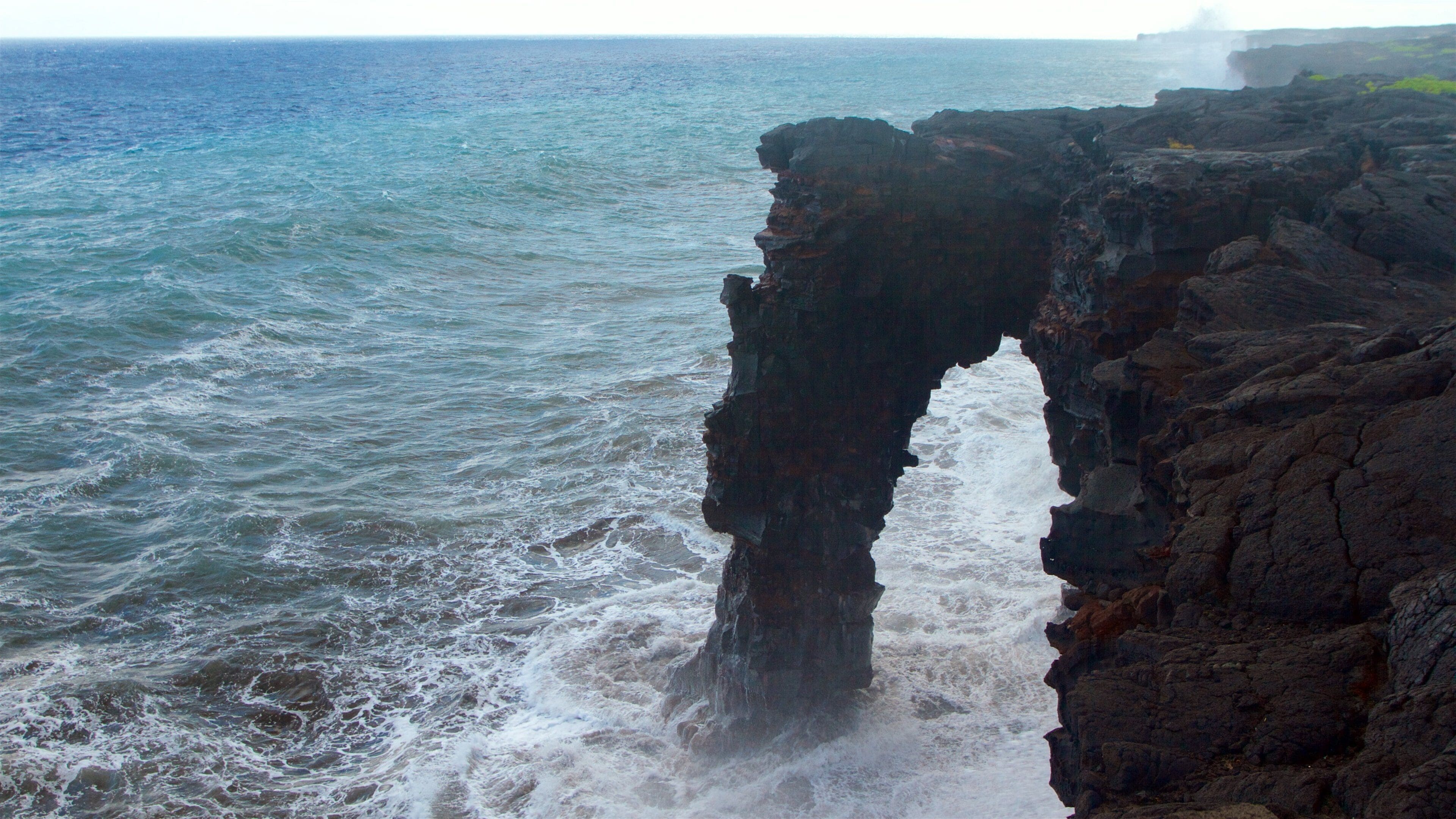 A coastal rock formation with waves crashing against it.