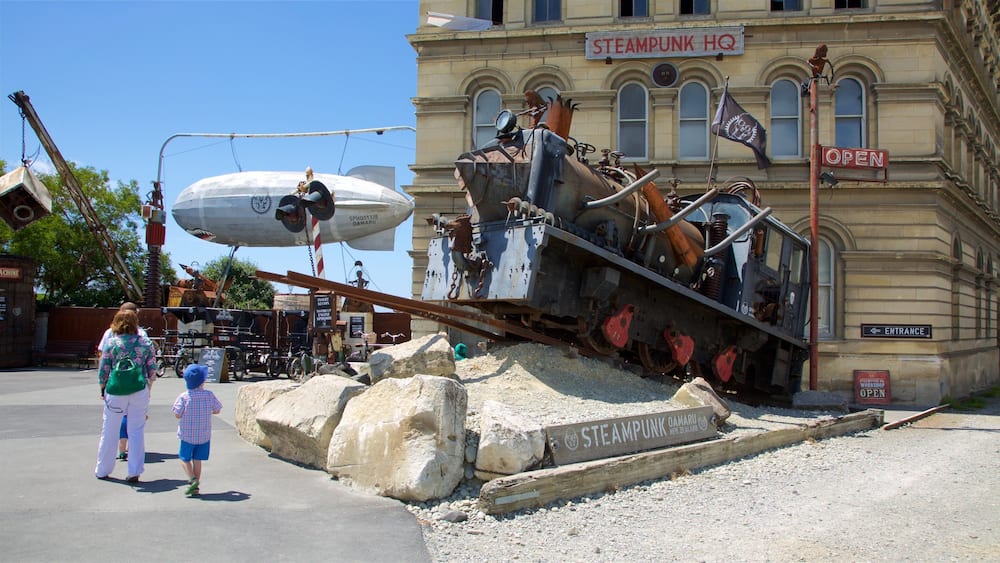 Un bâtiment portant l’inscription « QUARTIER GÉNÉRAL STEAMPUNK », avec une grande structure mécanique rouillée devant.