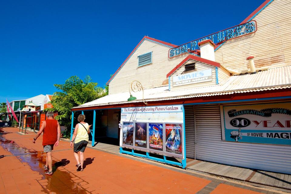 A vintage movie theater with a sign reading "The World's Oldest Operating Picture Gardens" and a poster advertising "Celebrating 100 Years of Movie Magic."