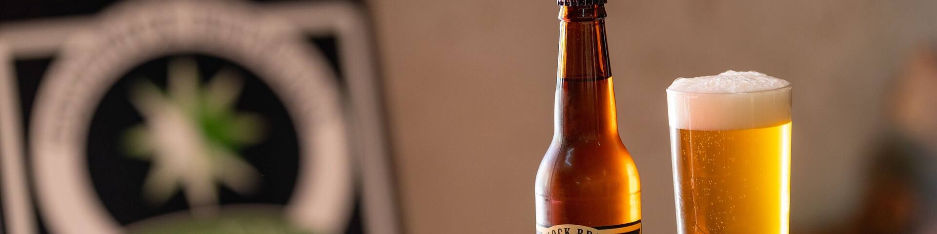 Una botella y un vaso de cerveza sobre una mesa de madera.