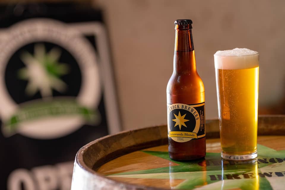 A bottle of beer and a glass of beer on a wooden table.