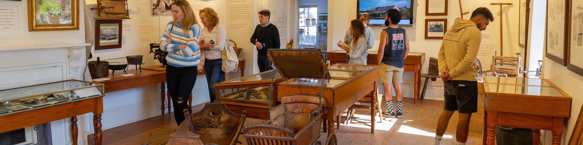 Interior de museo con exhibiciones históricas, incluyendo un carro de madera y varios artefactos expuestos.