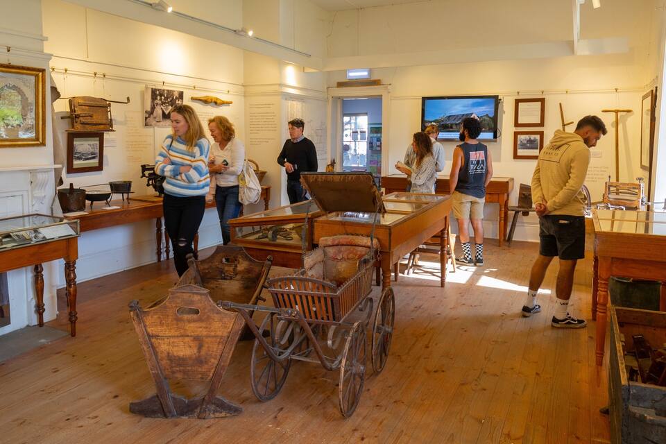 A museum interior with historical exhibits, including a wooden cart and various artifacts on display.