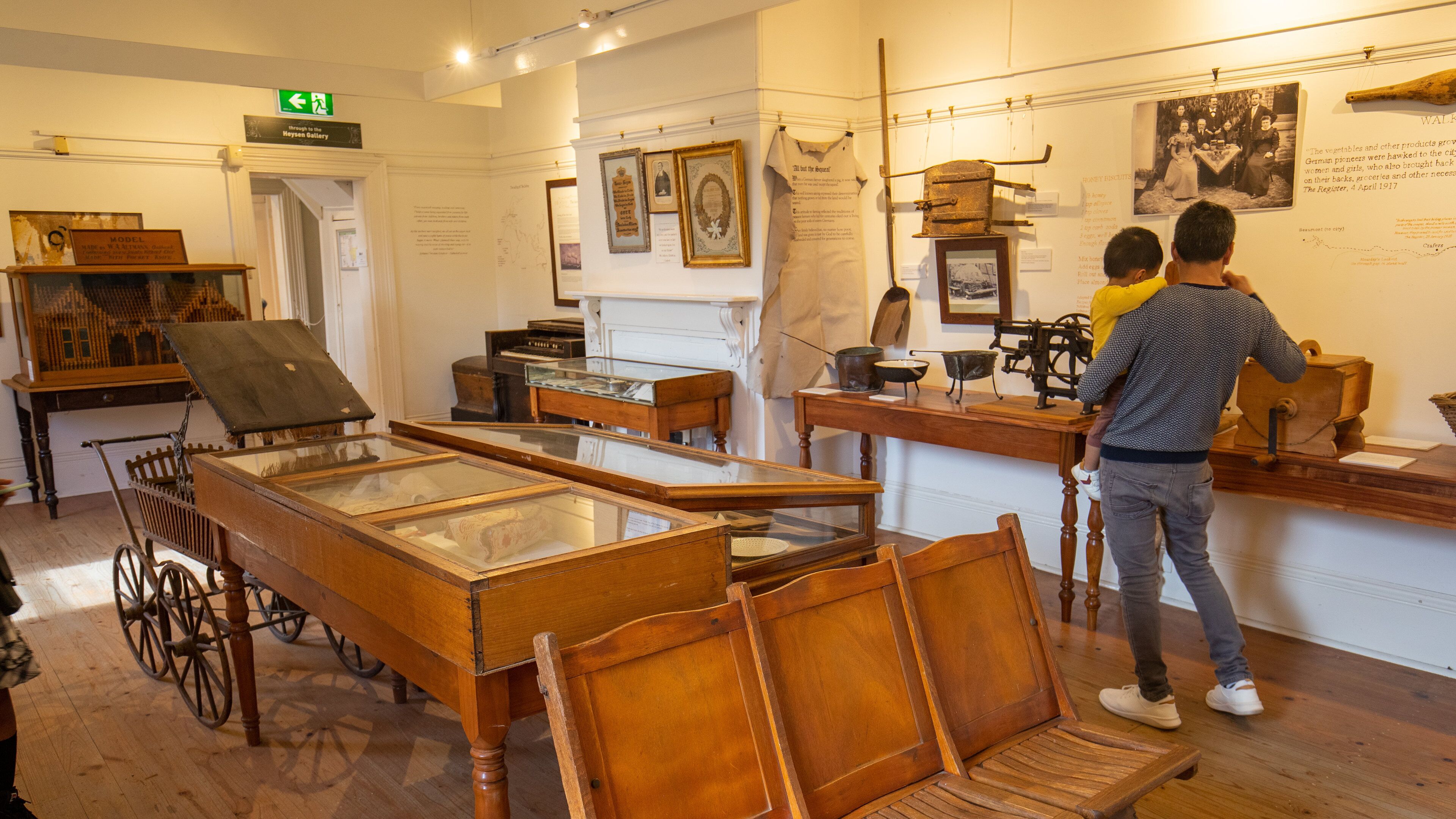 Een museumexpositie met historische objecten, waaronder een houten kar en een vitrine met voorwerpen.