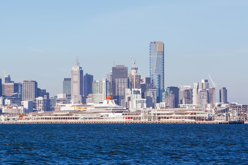 Un horizonte urbano con un edificio alto destacado y un crucero amarrado en un muelle.