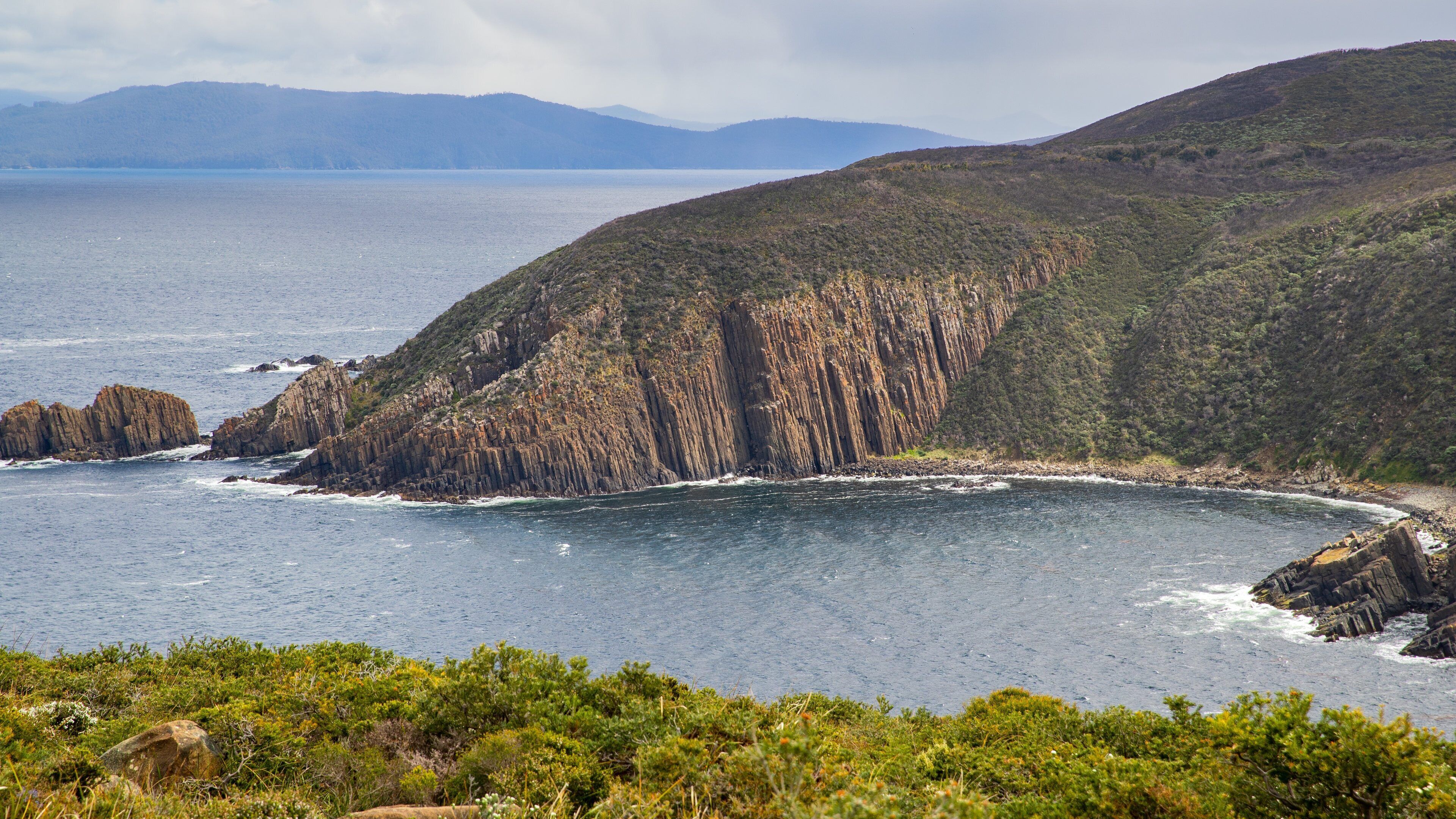 A coastal landscape with rugged cliffs and a calm sea.