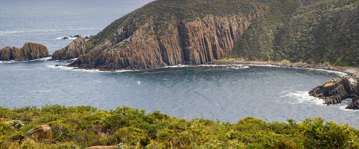A coastal landscape with rugged cliffs and a calm sea.
