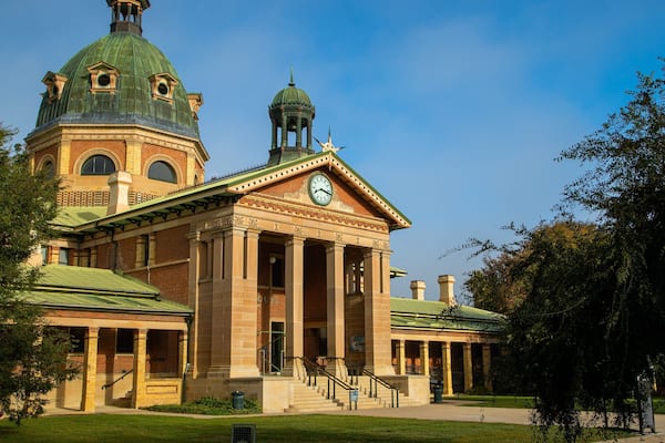 A large, historic building with a green dome and clock tower.