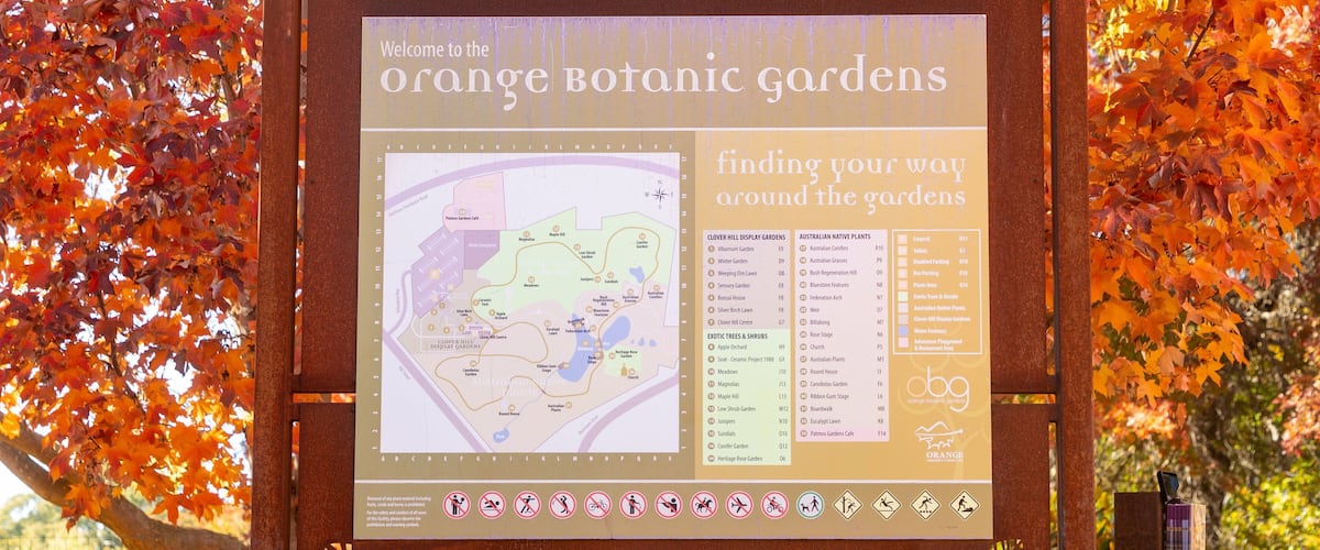 A signboard for Orange Botanic Gardens with a map and information about the gardens and facilities.
