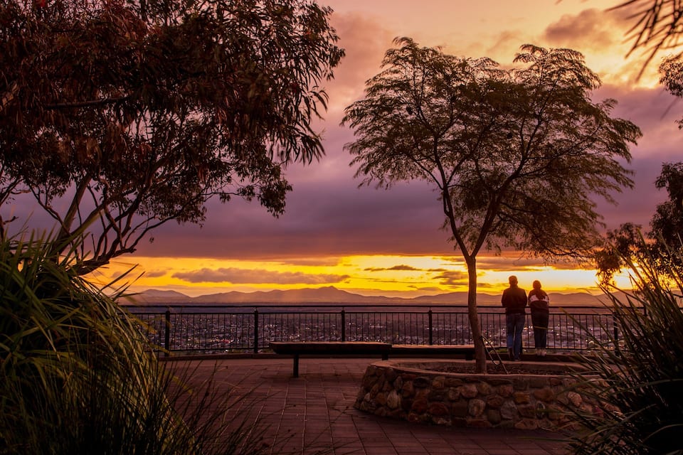 A sunset view with a bench and two people standing.
