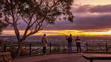 Vista do pôr do sol a partir de um banco de parque com vista para a cidade.