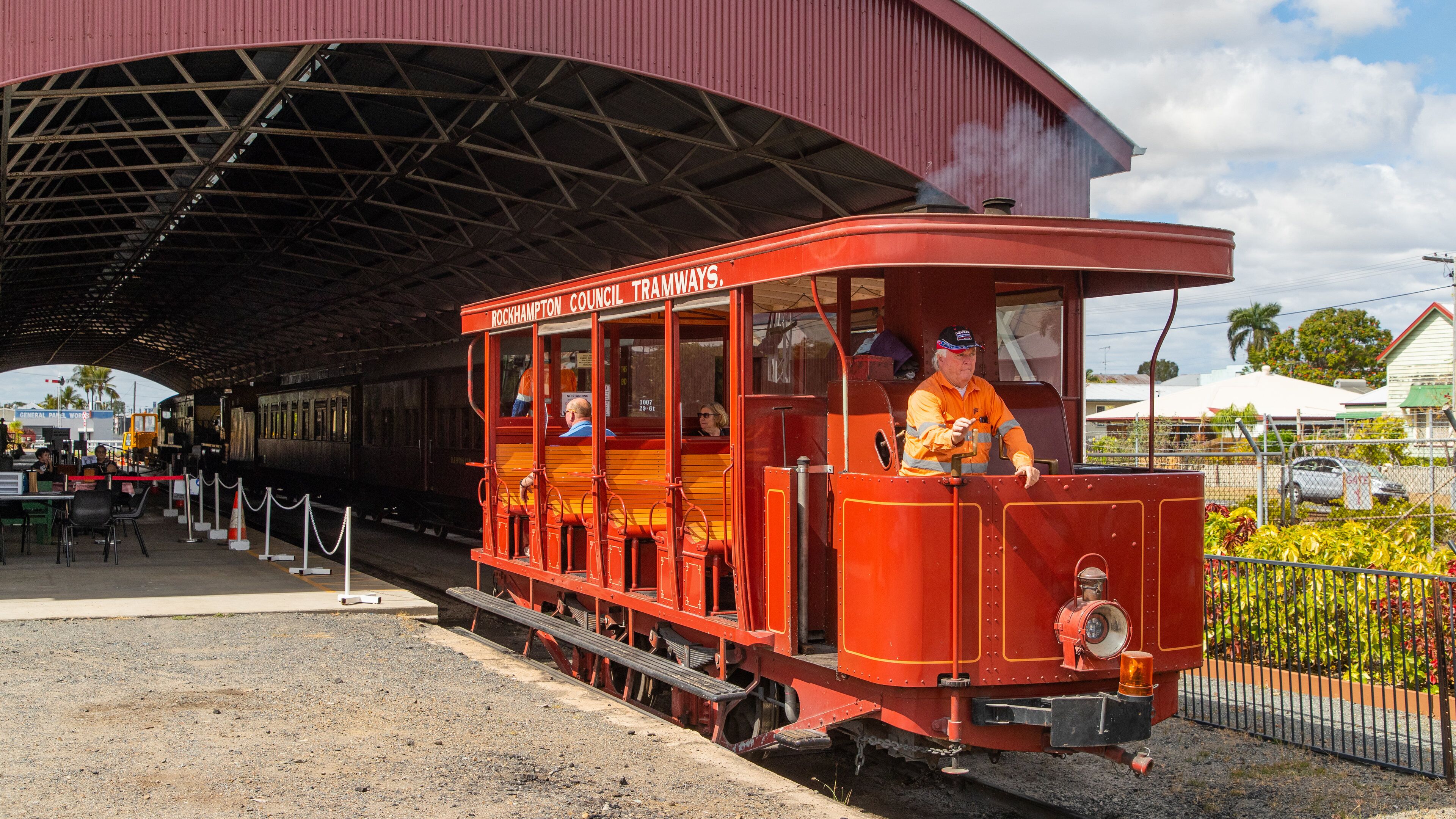 A red Rockhampton Council Tramways train at a station.