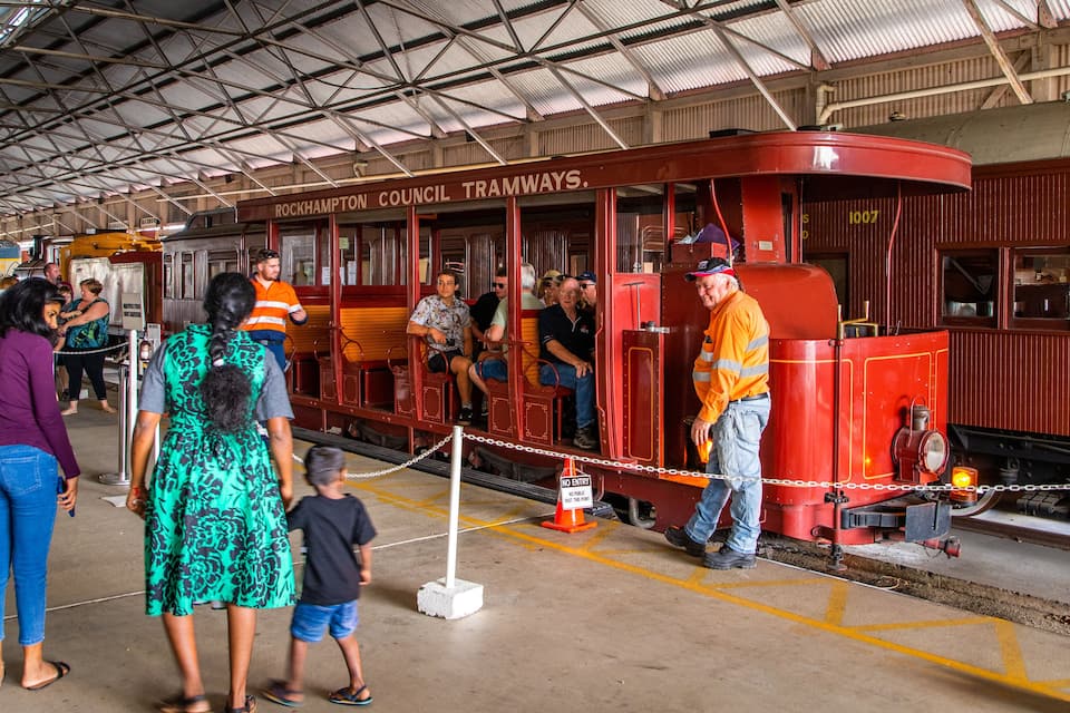 A red tramway at Rockhampton Colliery Tramways with people boarding and alighting.