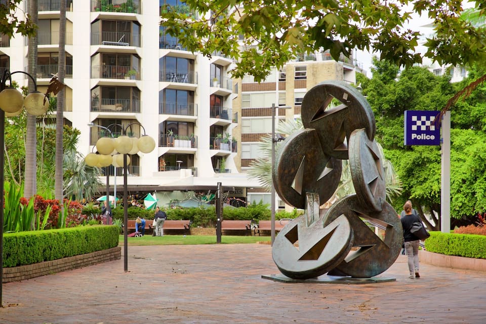 A large metal sculpture in a plaza with a police sign in the background.
