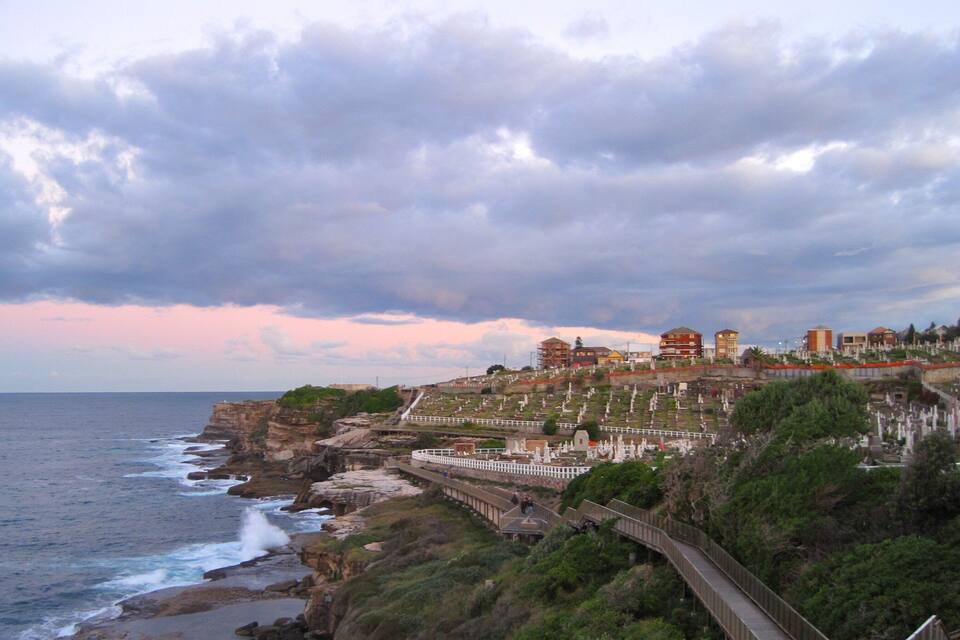 A coastal town with a sea wall, a promenade, and buildings on a hillside.