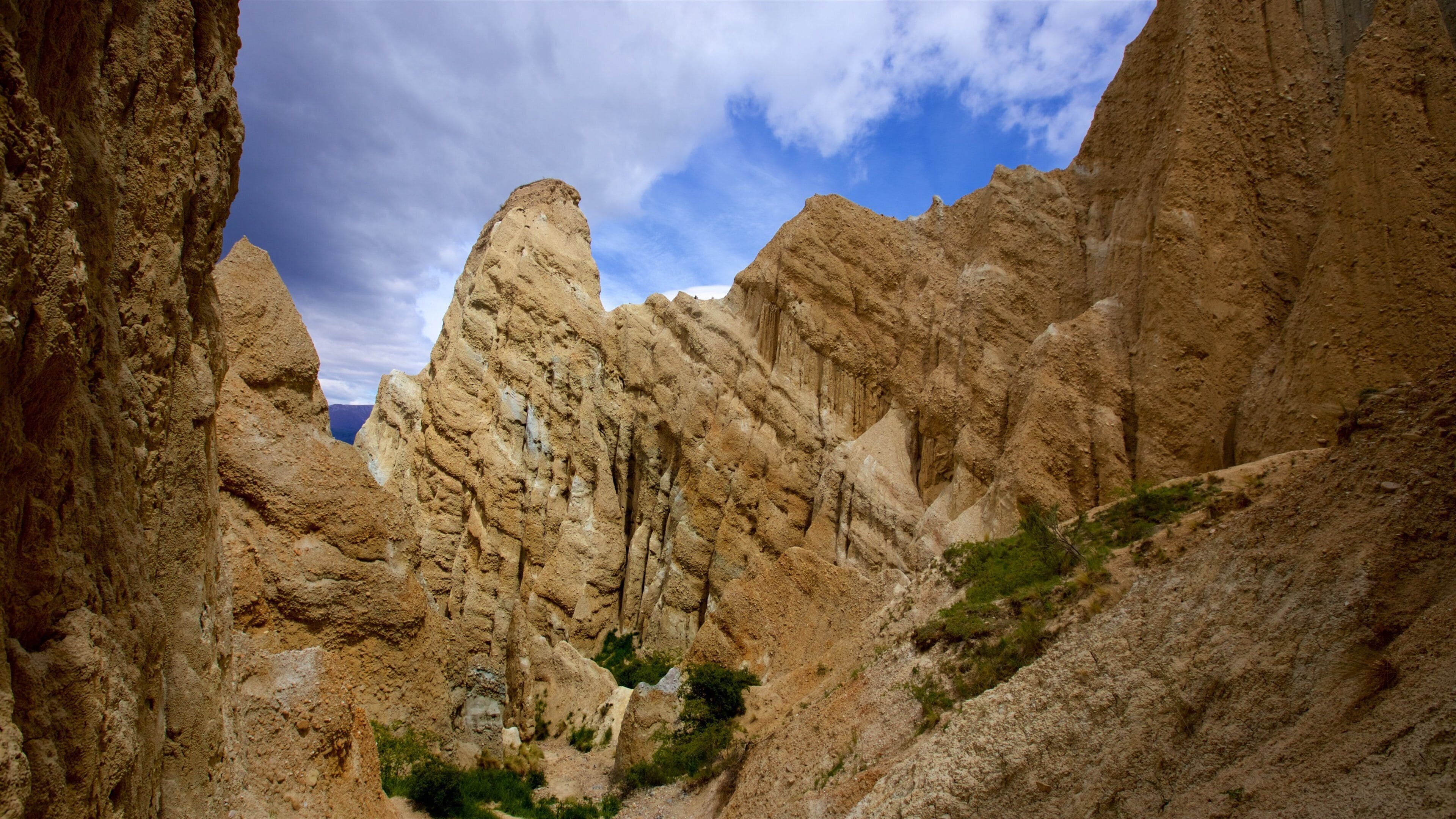 A canyon with rugged, layered rock formations and sparse vegetation.