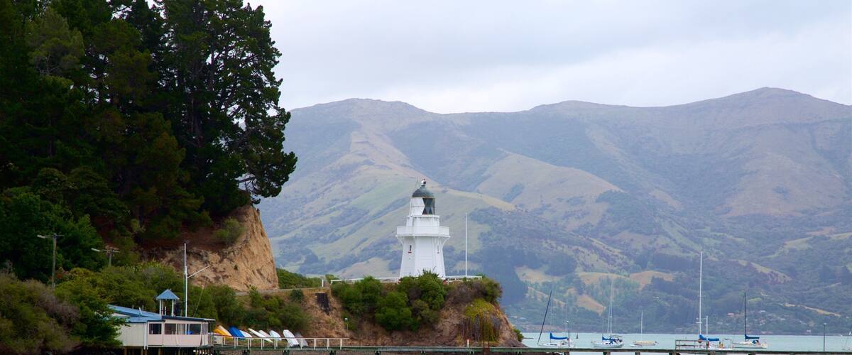Akaroa Lighthouse fasiliteter samt bukt eller havn, fyrtårn og rolig landskap