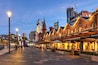 A city square with historic buildings, a modern skyscraper, and a construction crane in the background.