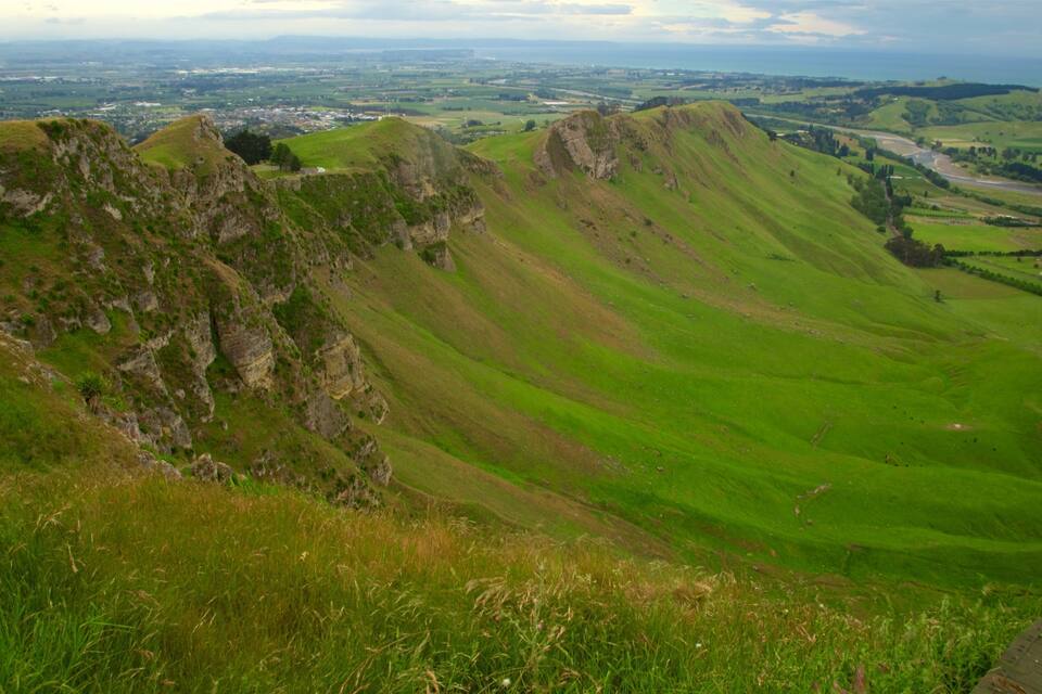 Rolling hills with a distant view of a town and a winding road.