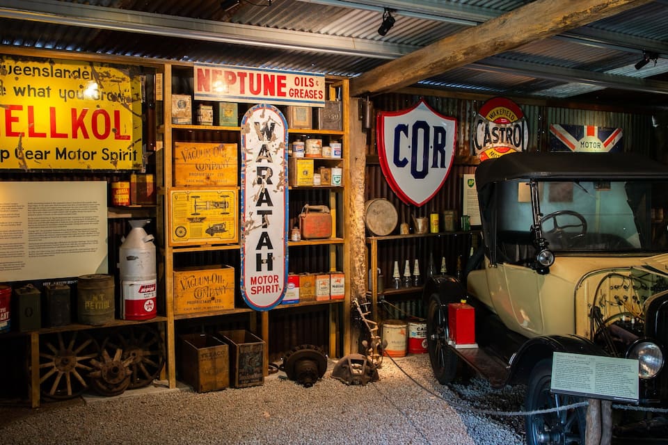 A vintage car exhibit with old signs and memorabilia.