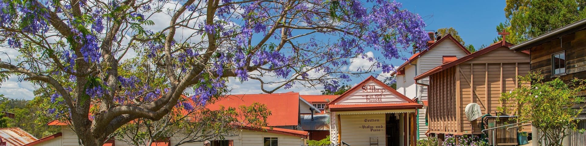 A rural setting with a large tree with purple flowers, a building labeled 'St. Mary's Church', and a sign for 'Tuition - Piano'.