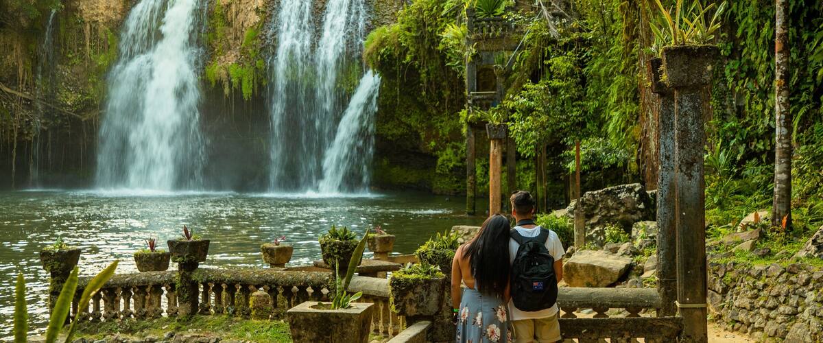 Paronella Park featuring a cascade and a lake or waterhole as well as a couple