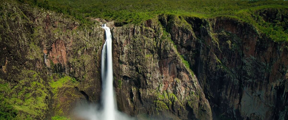 A waterfall cascading down a steep cliff surrounded by lush greenery.