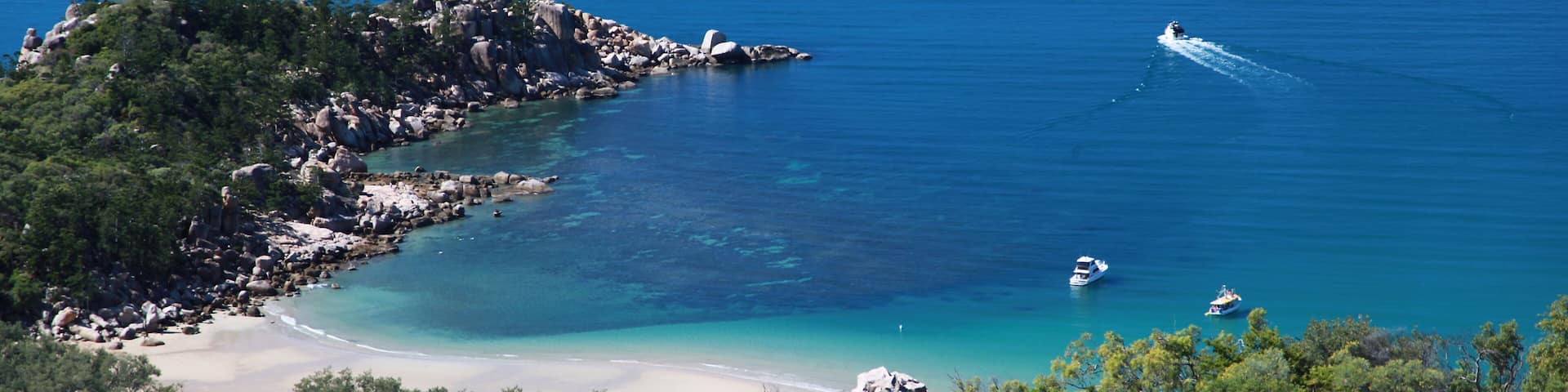 Un paisaje costero con aguas turquesas cristalinas, afloramientos rocosos y una playa arenosa.