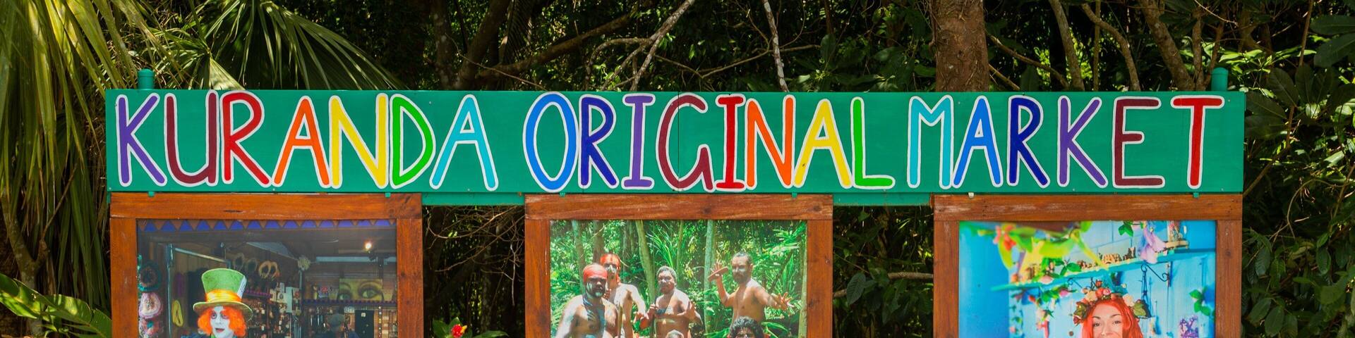 A sign for the Kuranda Original Market with colorful text and images of people.