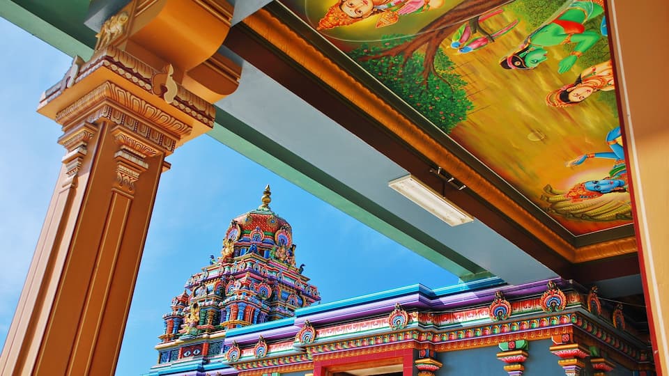 A colorful temple with intricate architecture and a detailed mural on the ceiling.