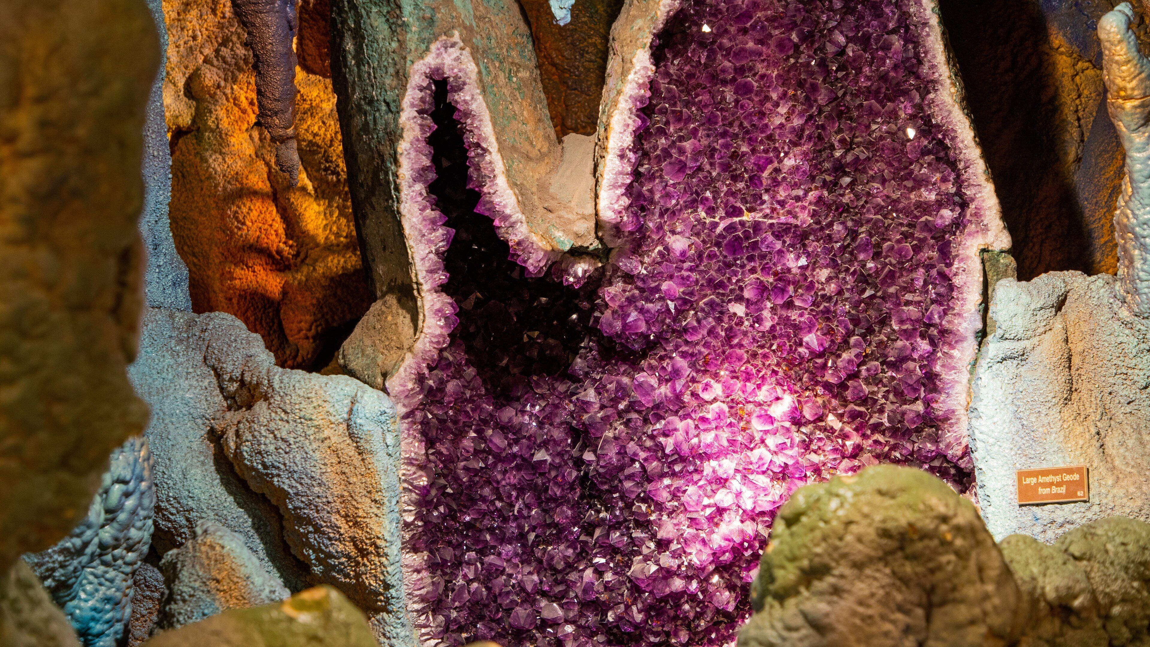 A large amethyst geode with purple crystals surrounded by rough rock formations.