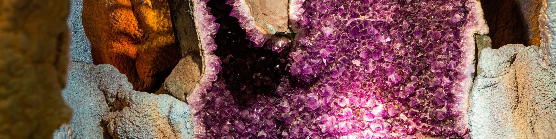 Una geoda de amatista grande con cristales morados rodeada de formaciones rocosas agrestes.