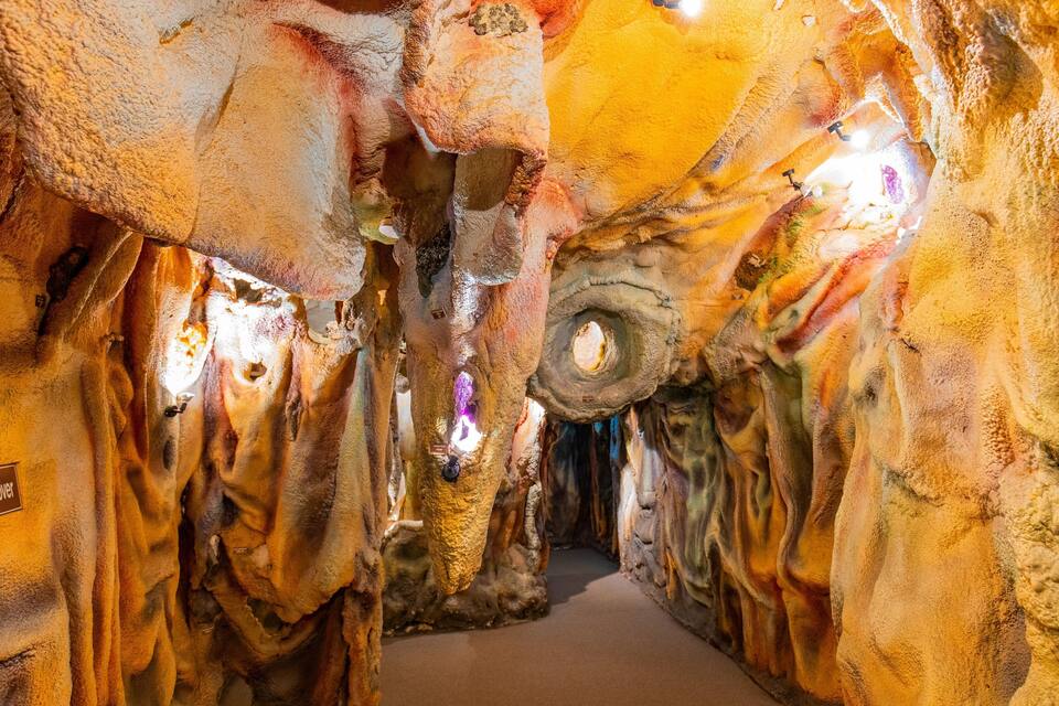 Une grotte ornée de stalactites et de stalagmites, éclairée par un système d’éclairage artificiel.