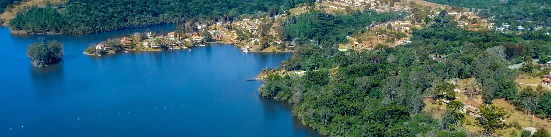 A large dam, a lake, and a densely forested area with scattered buildings.
